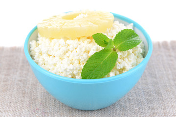 Bowl of tasty cottage cheese with pineapple, isolated on white