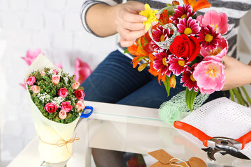 Female hands composing beautiful bouquet, close-up. Florist at