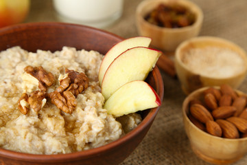 Tasty oatmeal with nuts and apples on table close up
