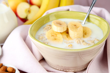 Tasty oatmeal with bananas and milk on table close up