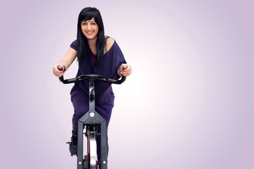 Naklejka premium Smiling woman training on exercise bike
