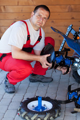 Worker mounting the tilling accessory on a cultivator