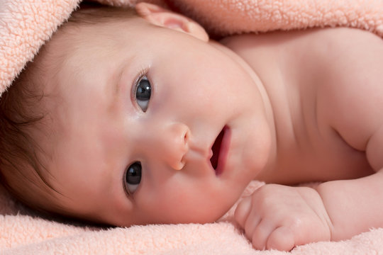 Adorable newborn baby girl is looking at the camera