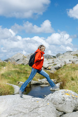 Woman hiker jumps over stones