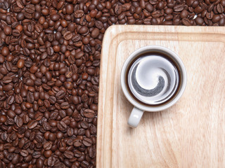 A cup of coffe on breadboard with coffee grains