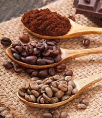green, roasted and ground coffee in wooden spoons