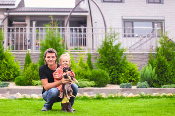 Young dad and his little daughter with her puppy on background