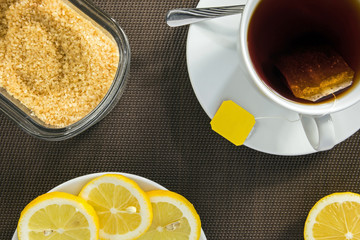 Tea cup, slices of lemon and brown sugar