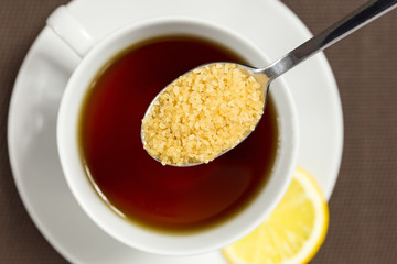 Adding brown sugar to a cup of tea