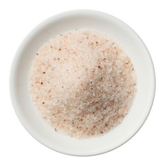 Himalayan pink salt pile in a plate isolated on white top view