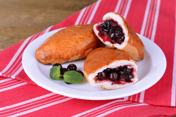 Fresh baked pasties with currant on plate on table close-up