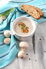 Mushroom soup in white pot, on napkin,  on wooden background