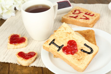 Delicious toast with jam and cup of tea on table close-up