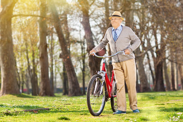 Obraz premium An elderly pushing his bike in the park