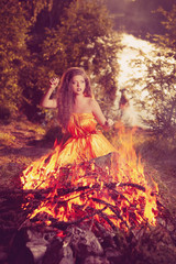 Fototapeta na wymiar Beautiful witch in the woods near the fire. Magic woman celebrat