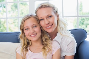 Fototapeta premium Happy mother and daughter sitting on sofa