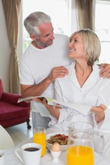 Couple reading newspaper while having breakfast