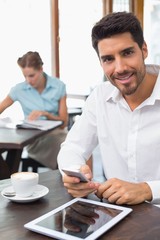 Smiling man text messaging in coffee shop