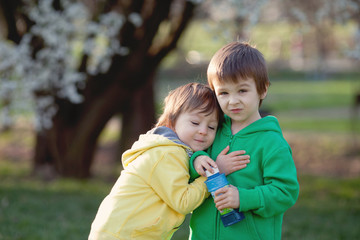 Two little kids in the park, having fun under a blooming tree