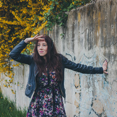 Pretty girl with long hair leaning against a concrete wall