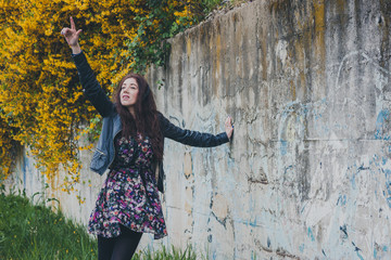 Pretty girl with long hair leaning against a concrete wall