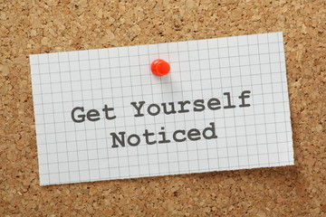 The phrase Get Yourself Noticed on a cork notice board
