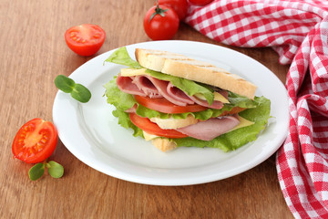 Tasty sandwich with ham on wooden table