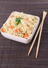 Tasty instant noodles with vegetables in bowl on table close-up