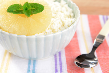 Bowl of tasty cottage cheese with pineapple on wooden table