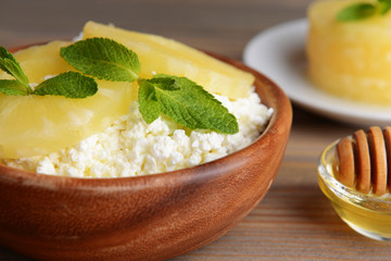 Bowl of tasty cottage cheese with pineapple on wooden table