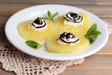 Tasty pineapple with cottage cheese on  wooden table