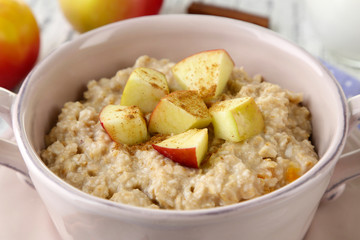 Tasty oatmeal with apples and cinnamon on table close up