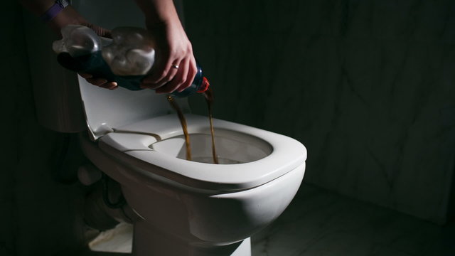 Pouring out cola into the toilet