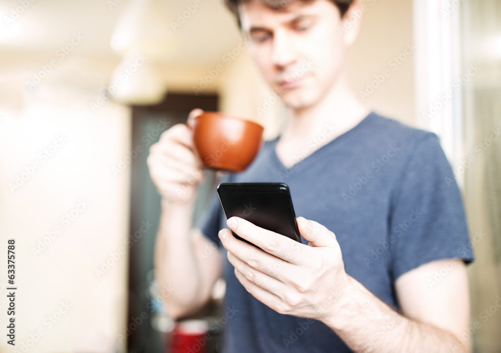 Wall mural man drinking coffee and using mobile smartphone