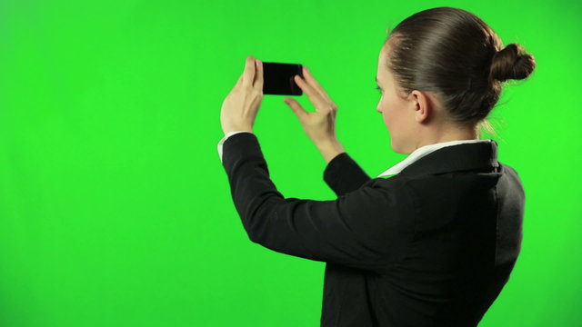 Businesswoman against a green screen uses mobile phone camera