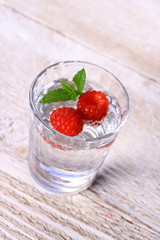 Water in glass, two raspberries and mint