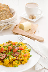 Scrambled eggs and bacon on white table
