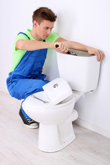 Plumber with toilet plunger on light background