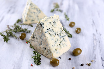 Tasty blue cheese with thyme and olives on wooden table