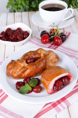 Fresh baked pasties with cherry on plate on table close-up