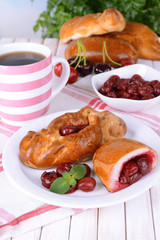 Fresh baked pasties with cherry on plate on table close-up