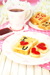 Delicious toast with jam and cup of tea on table close-up