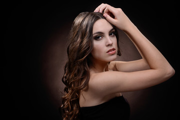 Naklejka premium Beautiful young woman with long hair on dark brown background