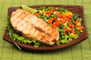 Tasty grilled salmon with vegetables, on bamboo mat