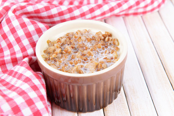 Boiled buckwheat with milk in bowl on table close-up