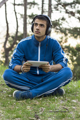 Obraz premium Man sits with tablet on the grass