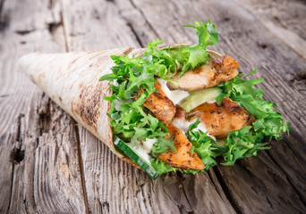Chicken strips in a Tortilla Wrap on wood.