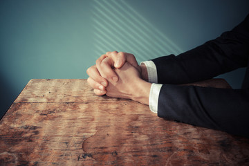 Man in suit praying at desk