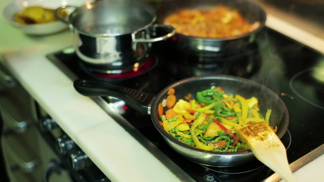 man's hands seasoning vegetables in a frying pan