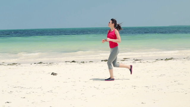 Young woman jogging on exotic beach, slow motion